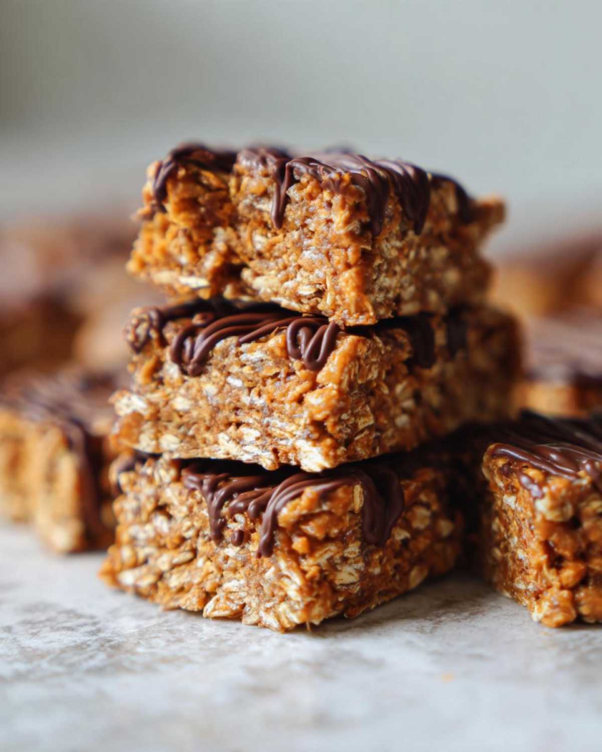 A stack of three homemade protein bars made with oats and drizzled with melted chocolate.