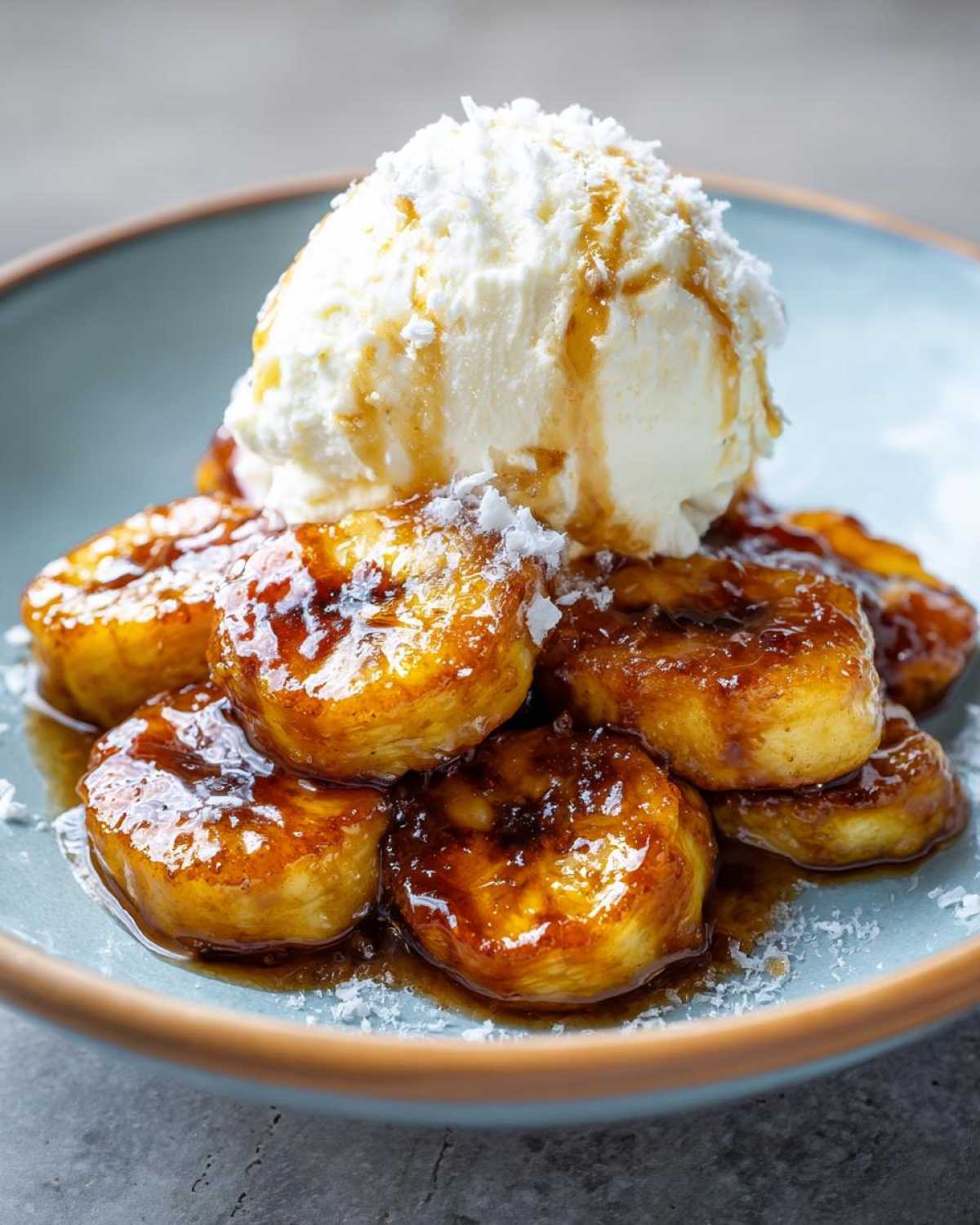 Close-up of caramelized bananas foster topped with vanilla ice cream and sauce.