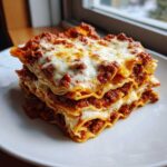 A thick, multi-layered slice of baked lasagna with rich meat sauce and melted cheese topping.