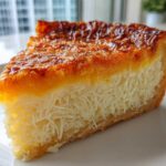 A close-up slice of cassava cake showing the shredded texture inside and a deeply caramelized, golden-brown topping.