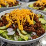 Close-up of a delicious cheeseburger bowl featuring seasoned ground beef, lettuce, pickles, and shredded cheese.