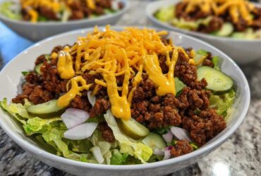 Close-up of a delicious cheeseburger bowl featuring seasoned ground beef, lettuce, pickles, and shredded cheese.