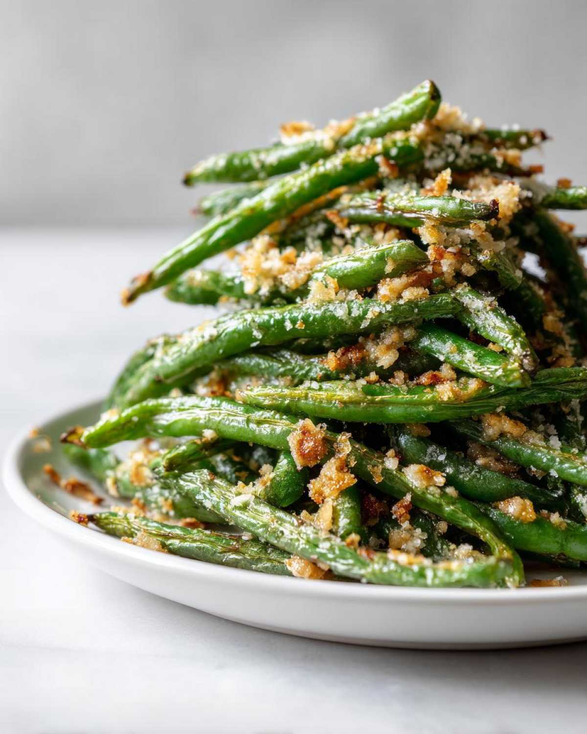 A tall stack of bright green beans topped with crispy breadcrumbs and Parmesan cheese.