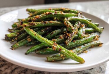 A close-up of bright green beans seasoned with garlic and spices, ready to serve.
