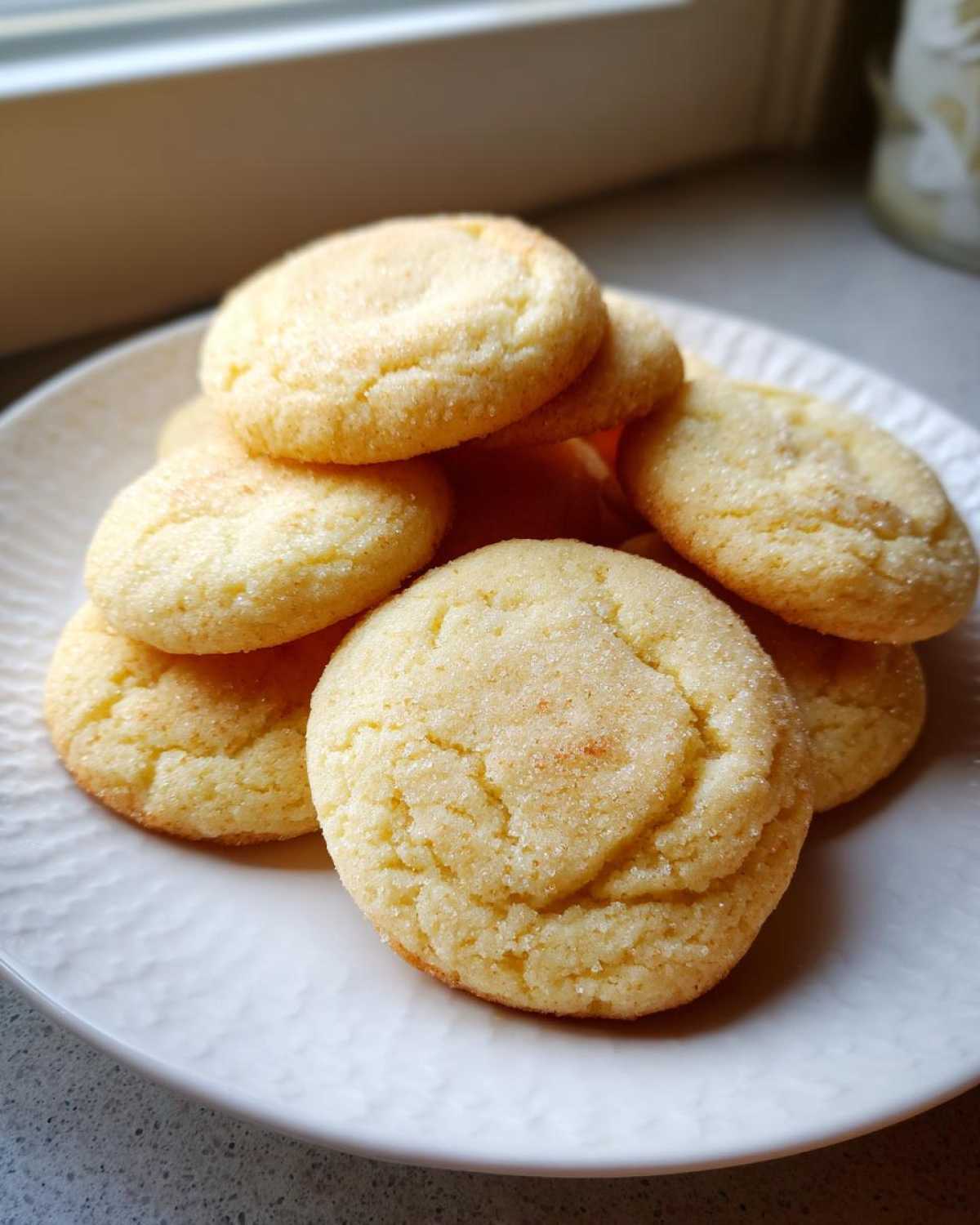 A close-up stack of freshly baked, round soft sugar cookies coated in sparkling sugar.