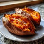 Two halves of perfectly baked sweet potatoes, fluffy inside and topped with coarse sea salt.