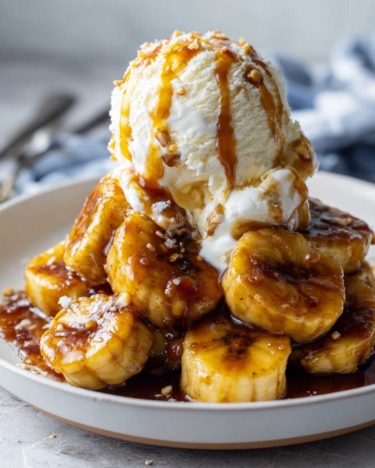 Close-up of warm, caramelized bananas foster topped with a scoop of vanilla ice cream and caramel sauce.