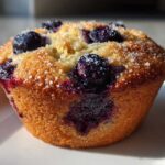 Close-up of a golden baked blueberry protein muffins topped with coarse sugar crystals.