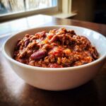 Close-up of a white bowl filled with thick, rich chili featuring ground meat and kidney beans, part of the best chili recipe.