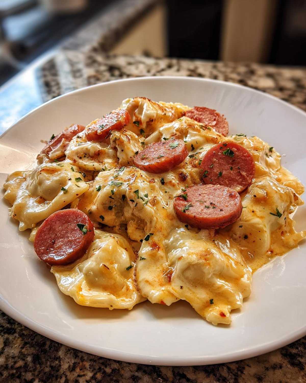 A close-up of a serving of cheesy pierogi casserole topped with slices of smoked sausage and parsley.