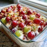 Close-up of creamy chicken salad chick grape salad topped with red and green grapes and chopped pecans.