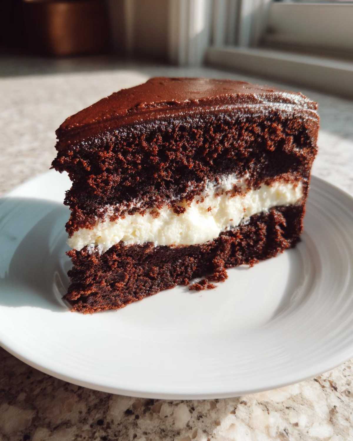 A rich slice of chocolate Italian love cake featuring dark layers and a thick white cream filling, served on a white plate.