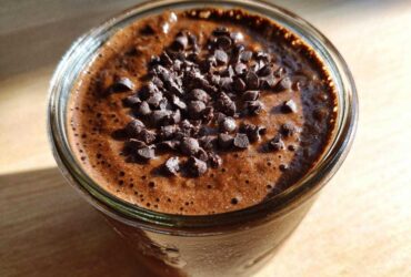 Close-up overhead view of rich chocolate overnight oats in a glass jar, topped generously with mini chocolate chips.