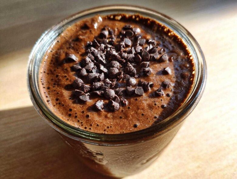 Close-up overhead view of rich chocolate overnight oats in a glass jar, topped generously with mini chocolate chips.