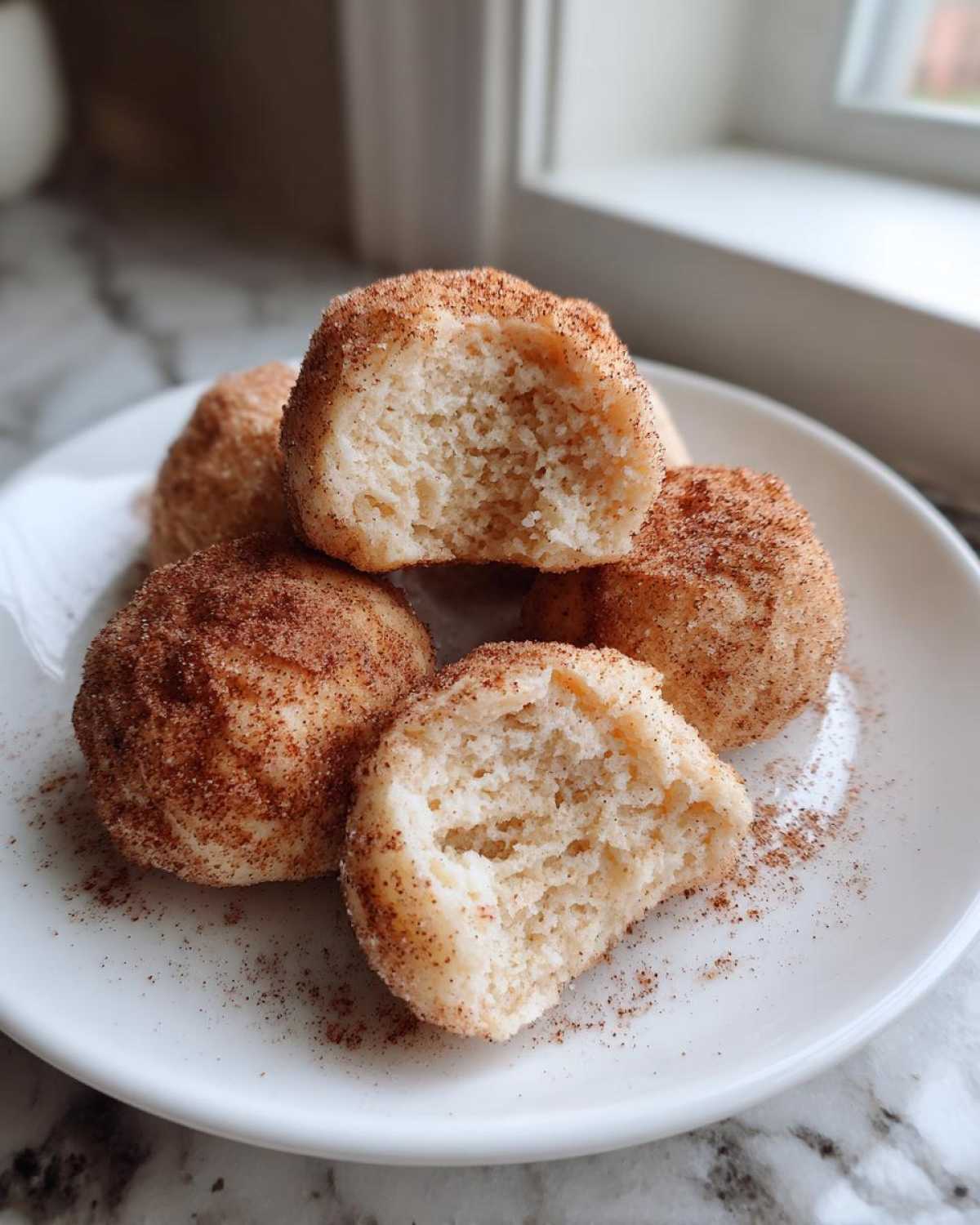 Close-up of soft cinnamon sugar snowball cookies, one broken open showing the fluffy interior texture.