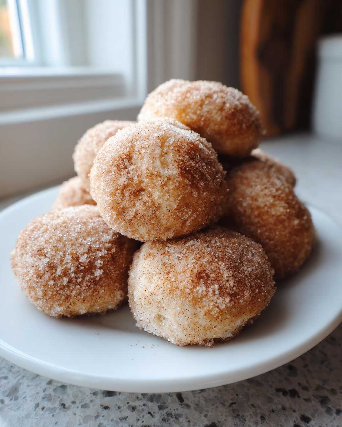 A stack of freshly made cinnamon sugar snowball cookies coated heavily in sparkling sugar and spice mix.