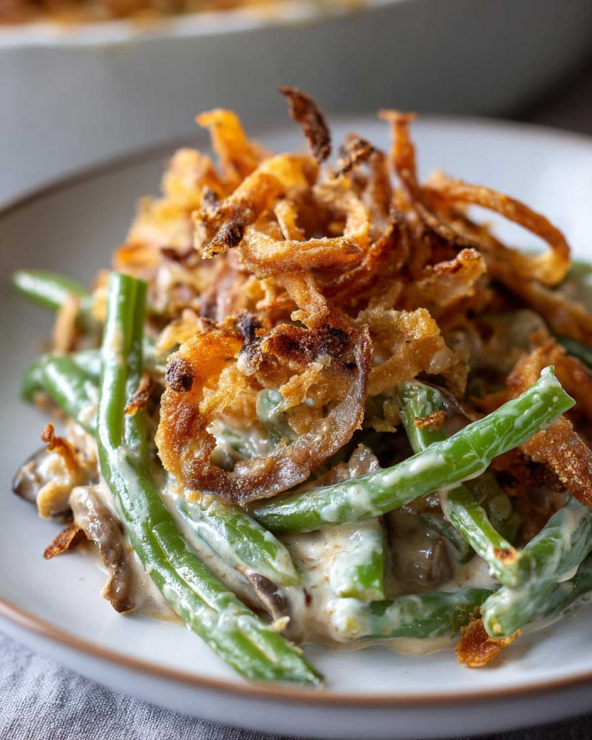 Close-up of a serving of creamy green bean casserole topped generously with crispy fried onions.