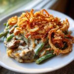 A close-up serving of creamy green bean casserole topped generously with crispy fried onions.