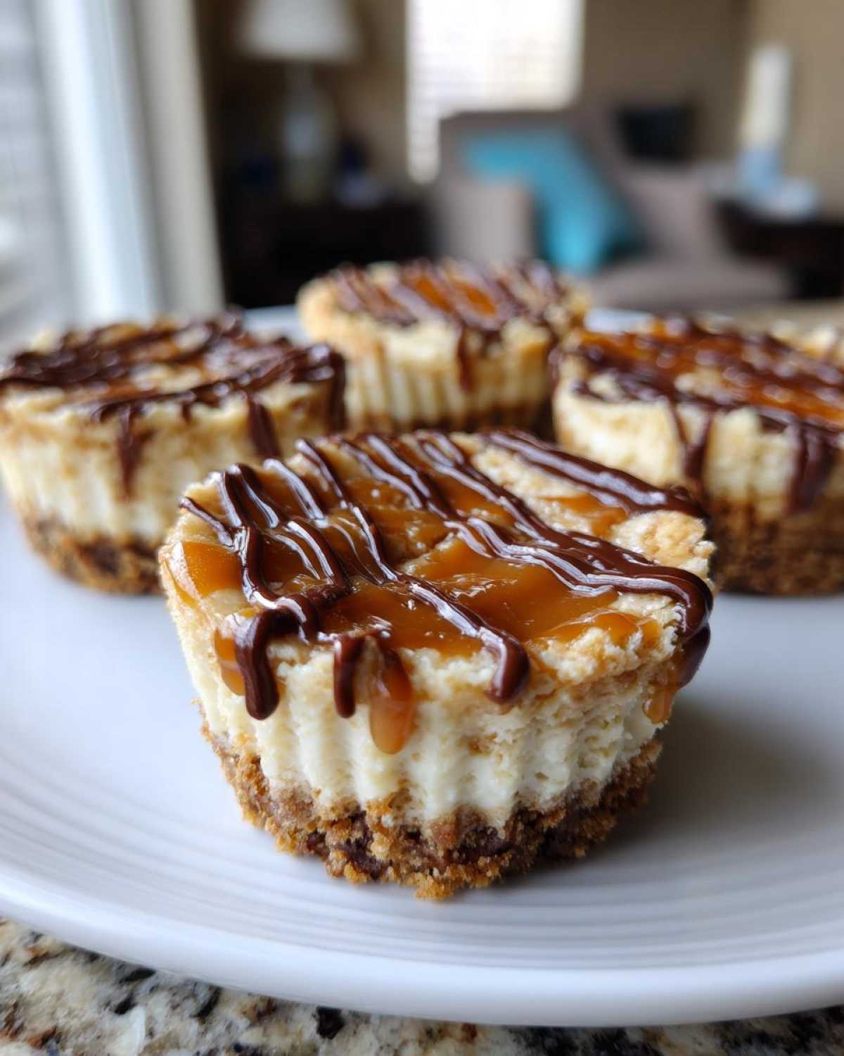 Close-up of four delicious cookie butter cheesecake cups topped with caramel and chocolate drizzle.