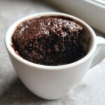 Close-up of a rich, dark chocolate Cottage Cheese Microwave Brownie baked inside a white mug.