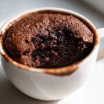 Close-up of a rich, dark chocolate Cottage Cheese Microwave Brownie baked in a white mug.