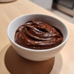 A close-up of thick, rich, homemade chocolate dip swirled in a small white bowl.