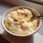 Close-up of a creamy bowl of rice pudding topped with a sprinkle of cinnamon, ready to eat.