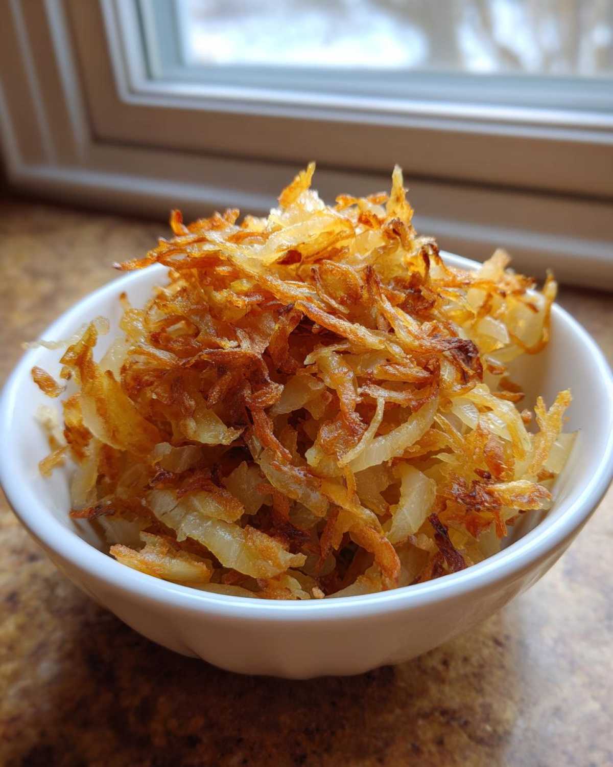 Close-up of a small white bowl filled with golden brown, crispy fried potatoes.