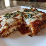 Close-up of a serving of Easy Chicken Parmesan with melted mozzarella, marinara sauce, and fresh basil.