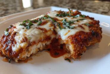 Close-up of a serving of Easy Chicken Parmesan with melted mozzarella, marinara sauce, and fresh basil.