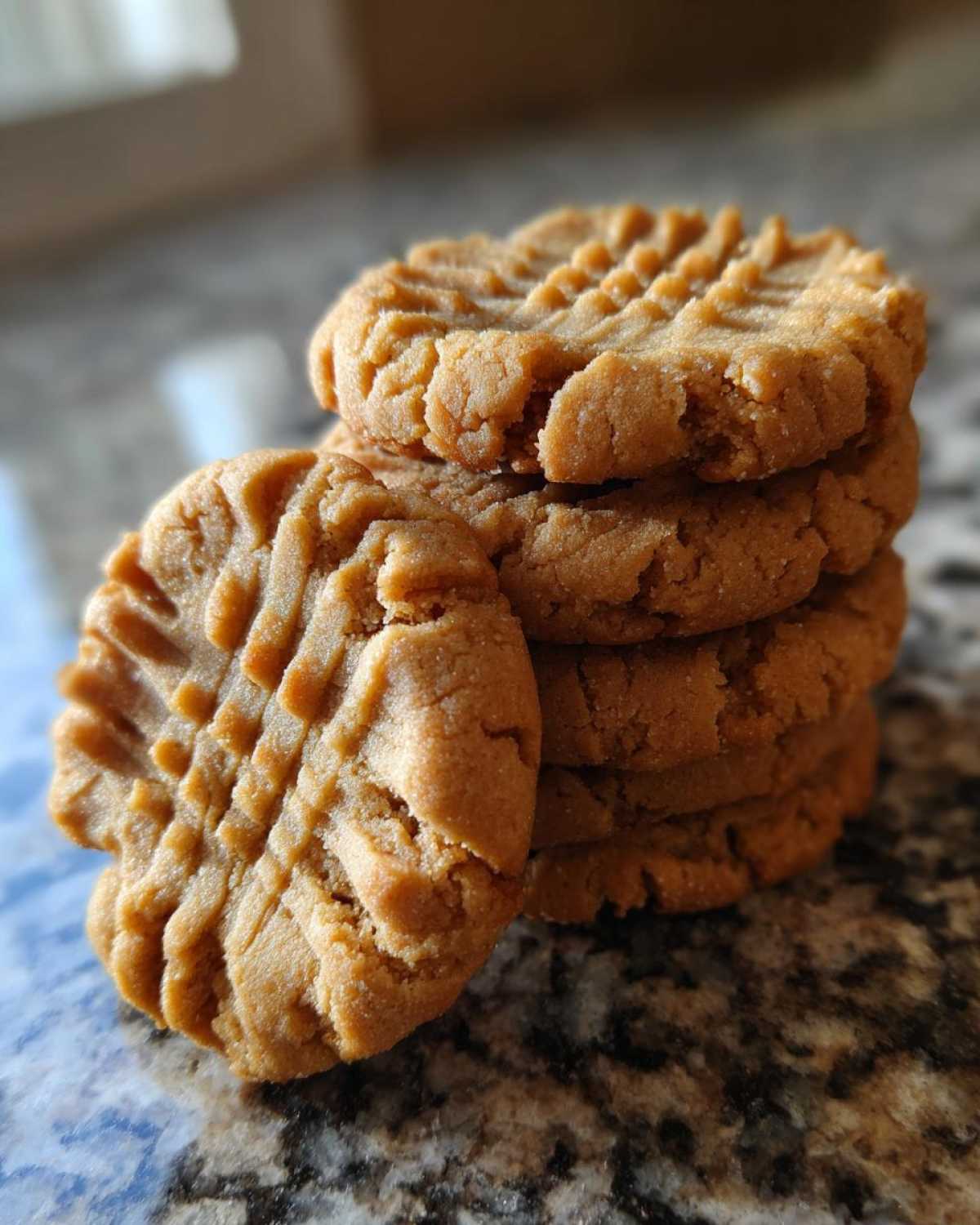 A stack of freshly baked Easy Peanut Butter Cookies showing the classic criss-cross fork marks.
