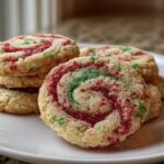 A stack of festive red and green pinwheel cookies rolled in sugar, displayed on a white plate.