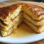 Cross-section view of a stack of fluffy almond flour pancakes drizzled generously with maple syrup.