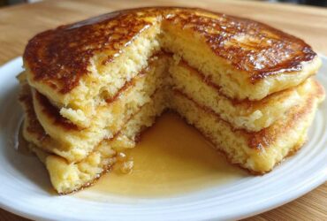 Cross-section view of a stack of fluffy almond flour pancakes drizzled generously with maple syrup.