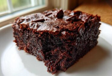 Close-up of a rich, dark, fudgy slice of black bean brownies topped with melted chocolate chips.