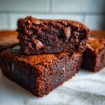 Close-up of two stacked, fudgy sweet potato brownies showing melted chocolate chips inside.