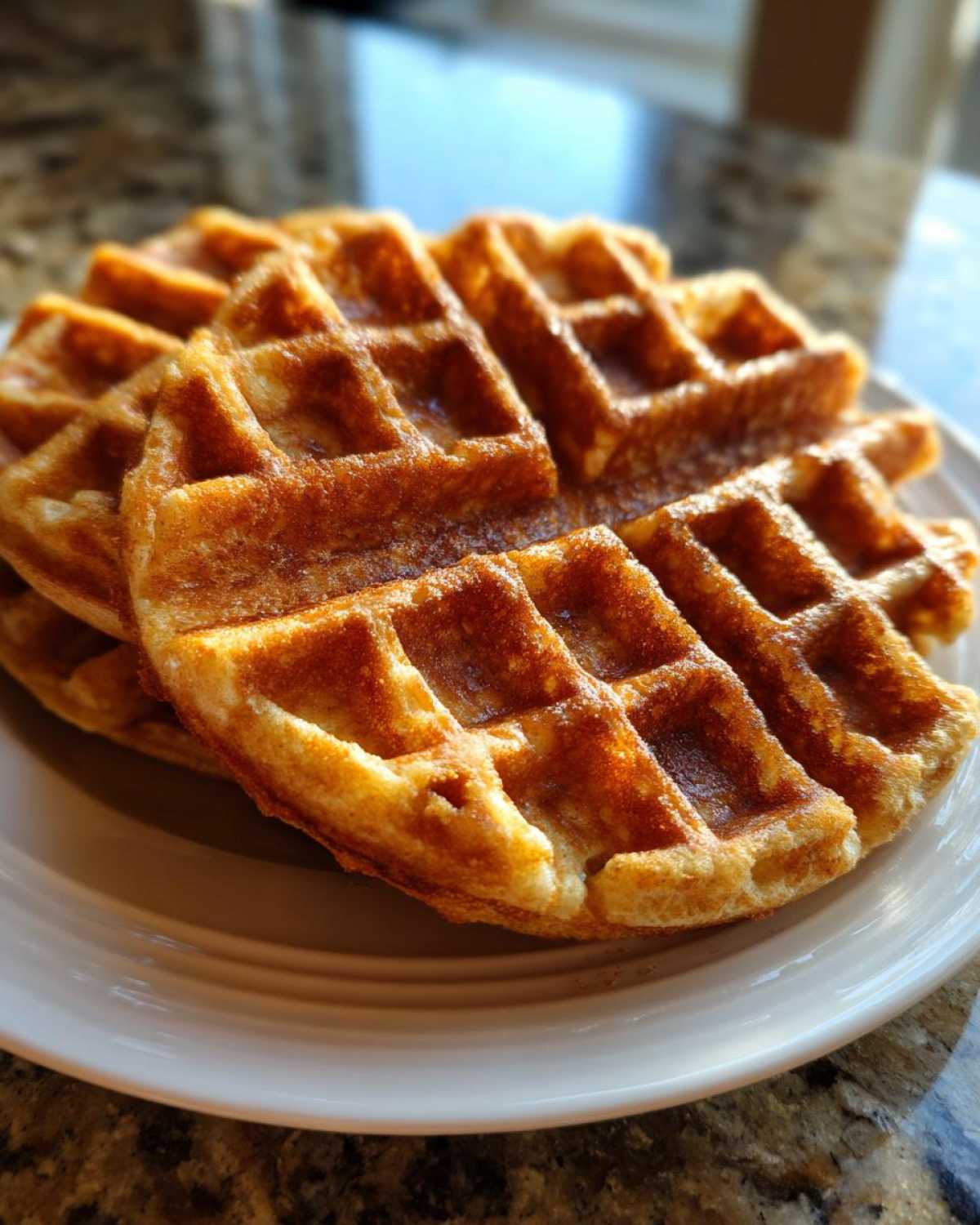 Close-up of a stack of golden brown, crispy high protein waffles served on a white plate.