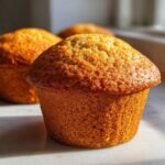 Close-up of a perfectly baked, golden brown honey bran muffin catching the sunlight.