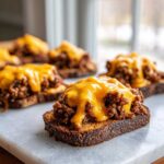 Close-up of open-faced sandwich featuring savory meat topping and melted cheddar cheese, part of the hanky panky recipe.