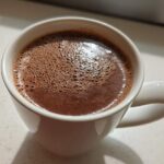 Close-up of rich, foamy homemade hot cocoa served in a white ceramic mug.