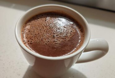 Close-up of rich, foamy homemade hot cocoa served in a white ceramic mug.