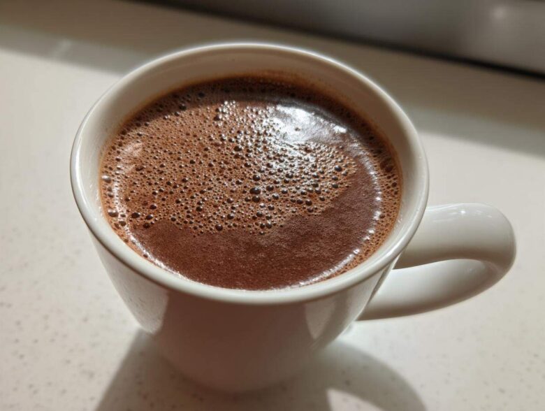 Close-up of rich, foamy homemade hot cocoa served in a white ceramic mug.