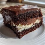 A decadent slice of Italian love cake featuring dark chocolate cake layers, white filling, and chocolate frosting.