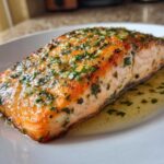 Close-up of a perfectly cooked, juicy air fryer salmon fillet topped with garlic and parsley.