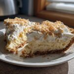 Two slices of creamy Million Dollar Pie with whipped topping and toasted coconut flakes.