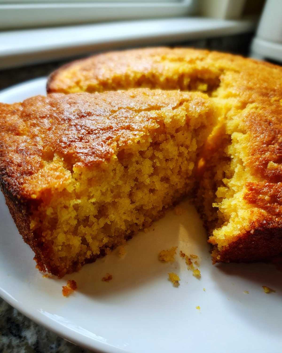 Close-up of a freshly cut piece of golden skillet cornbread showing its moist, crumbly texture.