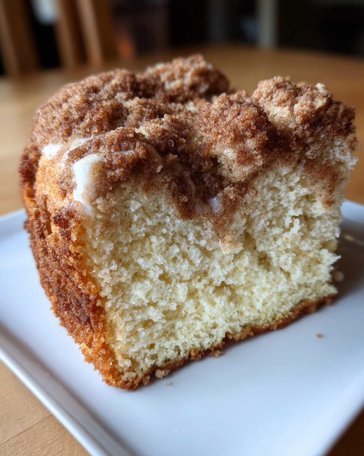 Close-up of a moist slice of sour cream coffee cake showing the tender crumb and thick cinnamon streusel topping.