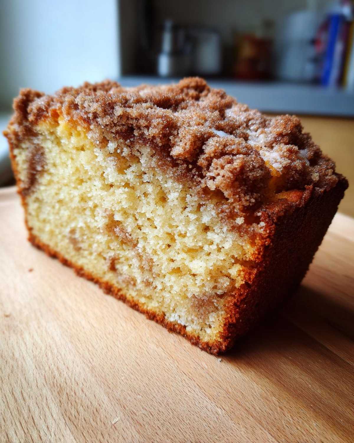Close-up of a moist slice of sour cream coffee cake showing the crumb and thick cinnamon streusel topping.