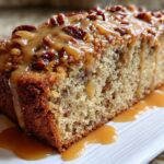 Close-up of a slice of moist sweet alabama pecan bread topped with a thick caramel glaze and pecans.
