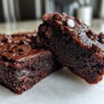 Close-up of two rich, fudgy sweet potato brownies topped with chocolate chips.